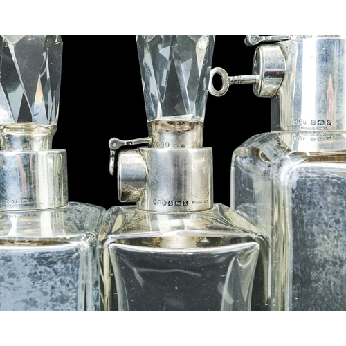295 - A matched suite of three Hukin & Heath silver mounted locking decanters. George V, each of plain rec... 