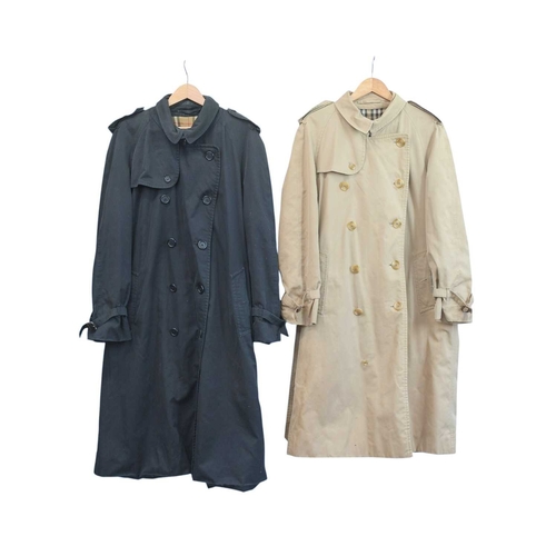 324 - Two Burberry trench coats. One black, one tan, both with a chest measurement of approximately 21