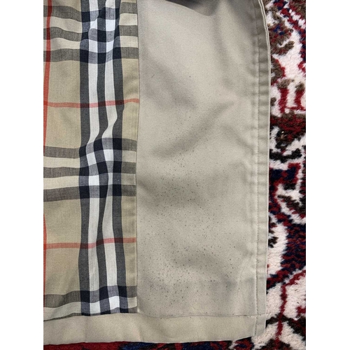 324 - Two Burberry trench coats. One black, one tan, both with a chest measurement of approximately 21