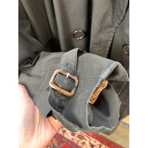 324 - Two Burberry trench coats. One black, one tan, both with a chest measurement of approximately 21