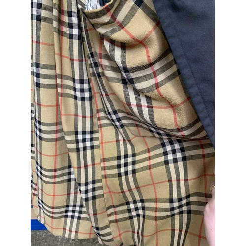 324 - Two Burberry trench coats. One black, one tan, both with a chest measurement of approximately 21