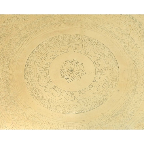 34 - An Eastern brass topped tray table. On a turned folding stand, height 71cm, diameter 57cm, together ... 