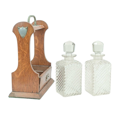 9 - An Edwardian oak two bottle tantalus. With plated mounts, the blown glass decanters with cut stopper... 