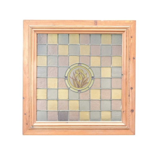 208 - A framed stained glass panel. Leaded glass squares in pink, grey and yellow with a central floral ro... 