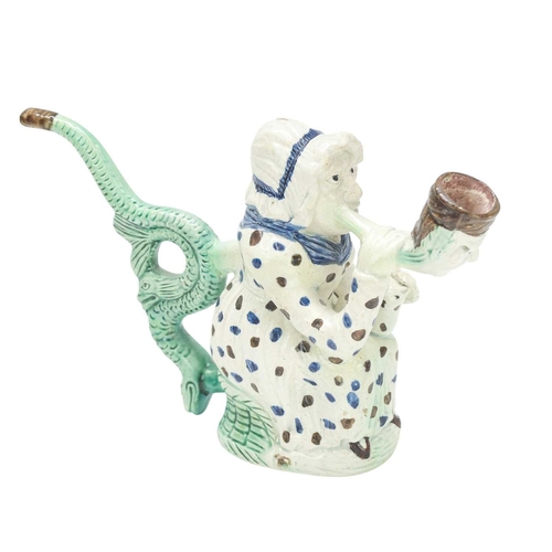 595 - A creamware Martha Gunn pipe. Circa 1790, modelled as the seated woman wearing a blue and brown spot... 