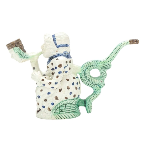 595 - A creamware Martha Gunn pipe. Circa 1790, modelled as the seated woman wearing a blue and brown spot... 