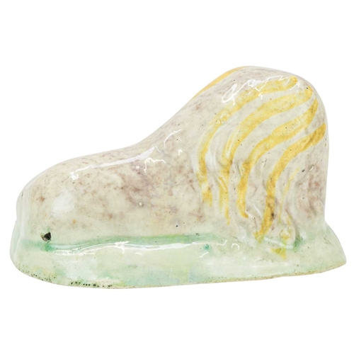 600 - A Pratt ware figure of a recumbent lion. Circa 1820, with ochre, brown, and green painted decoration... 