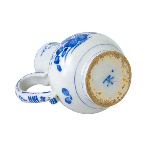 612 - An 18th century Delft jug. Blue painted with floral designs and a moulded face to the spout, height ... 