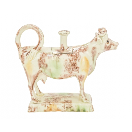 629 - A creamware Whieldon type cow creamer and cover. Circa 1760-1770, with sponged brown, green and ochr... 
