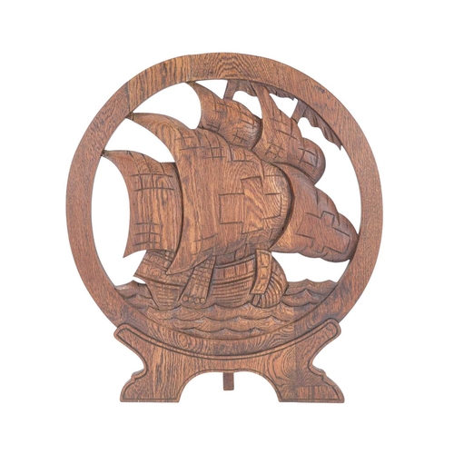 717 - An arts and crafts carved oak fire screen. Of circular form, carved with a galleon on high seas, hei... 