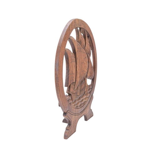 717 - An arts and crafts carved oak fire screen. Of circular form, carved with a galleon on high seas, hei... 
