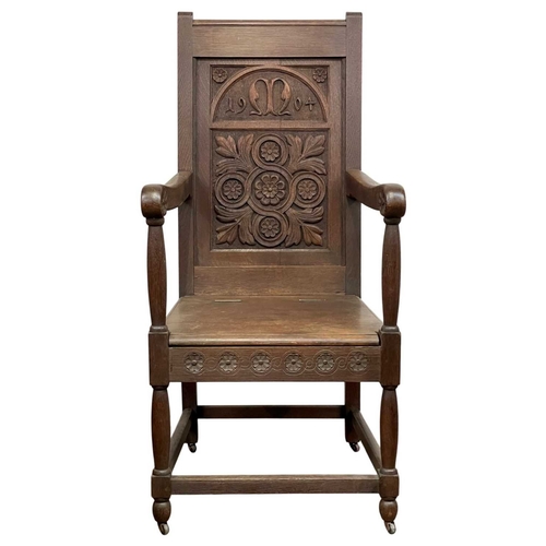 720 - A carved oak wainscot armchair. The panel back dated 1904, and initialled M with a leaf and flowerhe... 