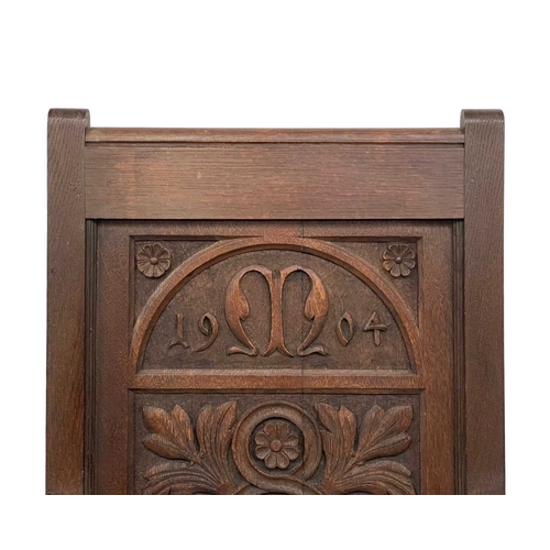 720 - A carved oak wainscot armchair. The panel back dated 1904, and initialled M with a leaf and flowerhe... 