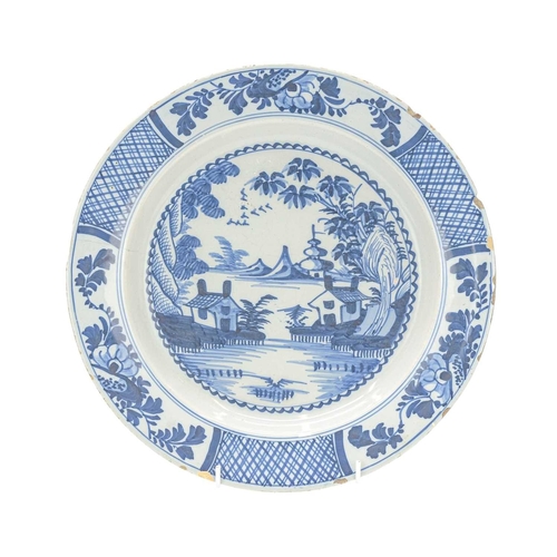 730 - An English blue and white Delft platter. Circa 1770, painted with lakeside houses and buildings, dia... 