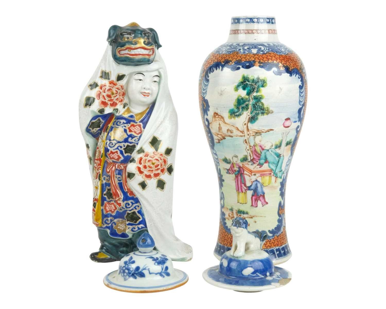 A Japanese porcelain figure of a child wearing a cloak with a lion mask ...