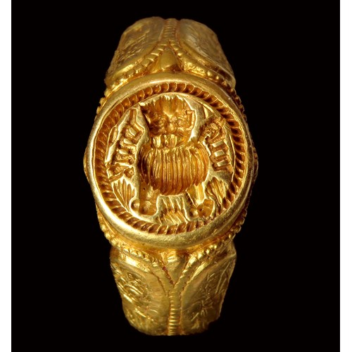 Medieval gold iconographic signet ring. The hoop has a moulded ropework pattern divided by a circumferential beaded line. The line is bifurcated at the shoulders before framing the bezel in a manner which echoes the clawed setting of contemporary gem-set rings. The shoulders are sub-triangular in section and each has a pair arched panels displaying iconographic engravings. The four panels depict Saint Michael, Saint Christopher, the Holy Trinity and Madonna & Child. The raised circular bezel is deeply engraved with the figure of a facing lion and the blackletter motto either side appears to read 'du:vie', French for 'of life', all within a circular beaded border.