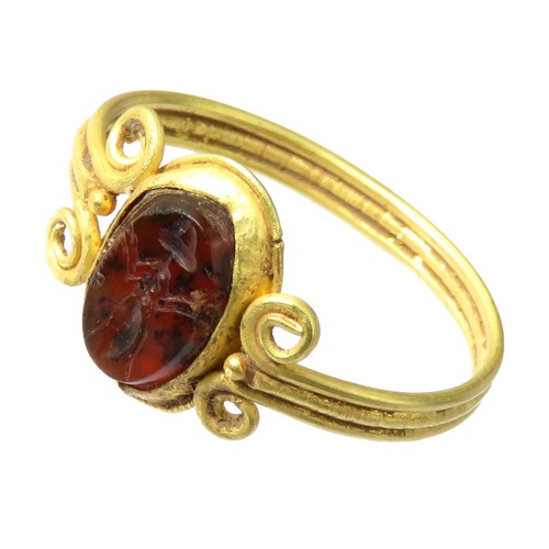 59 - Greek Intaglio Gold Ring. Circa 5th-4th century BCE. A polished garnet intaglio depicting a stylised... 