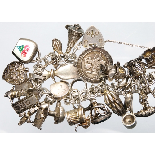 77 - Silver charm bracelet with approximately 30 charms. 7