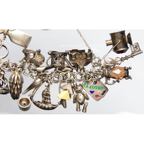 77 - Silver charm bracelet with approximately 30 charms. 7