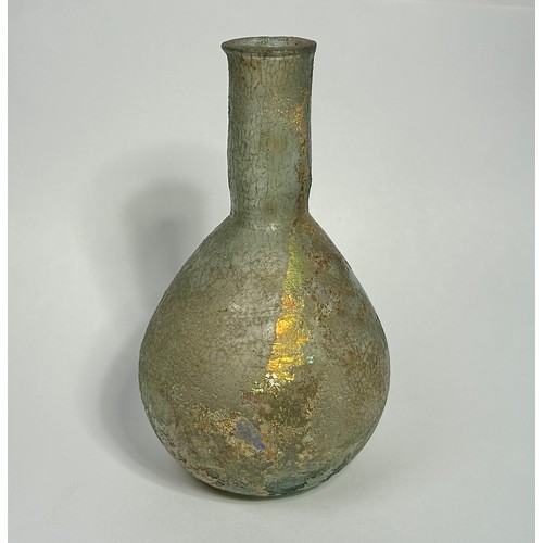 39 - Roman glass bottle. Circa 2nd century CE. 85mm x 35mm. A bulbous body with a straight sided narrow n... 