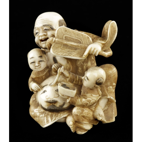 911 - An ivory okimono of a mask maker with his children assisting 2 1/2