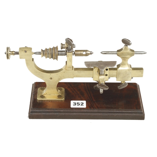 352 - A watchmakers brass mandrel on wood base G+