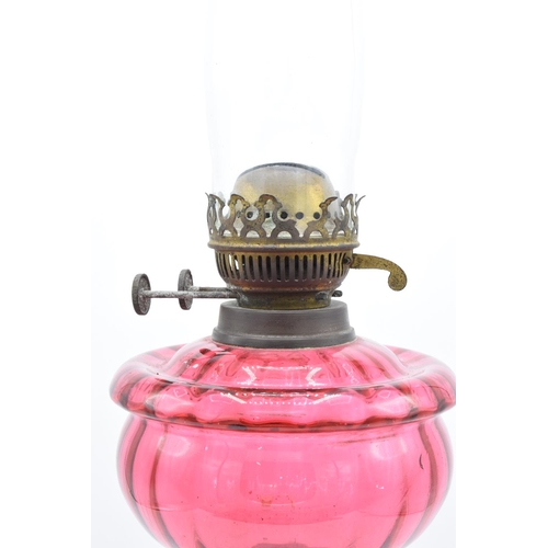 273 - Victorian cranberry oil lamp with a later chimney. Untested condition. Some damage to metalwork. See... 