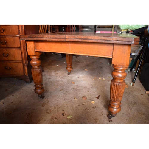 325 - Early 20th century golden oak dining table with a spare leaf and handle. In good condition with age ... 