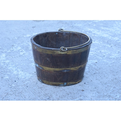 317 - Antique wooden and brass coopered oval bucket with brass handle. Some oxidation on the brass. Genera... 