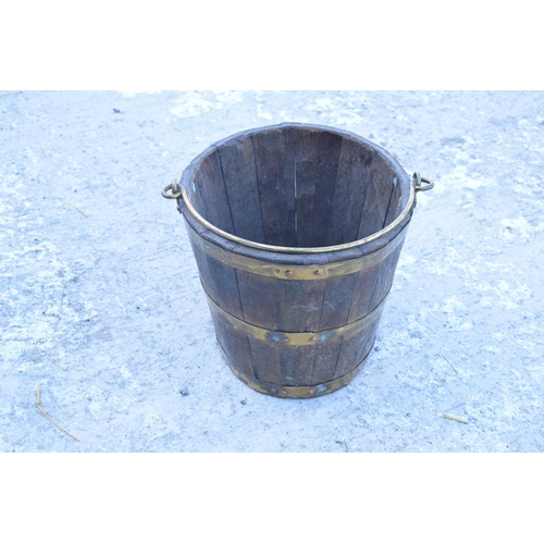 317 - Antique wooden and brass coopered oval bucket with brass handle. Some oxidation on the brass. Genera... 