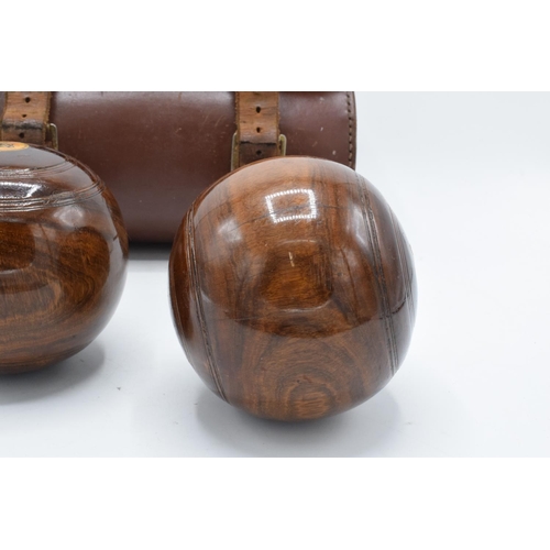 101 - A cased pair of turned 20th century lawn bowls in a leather carry case with monograms.