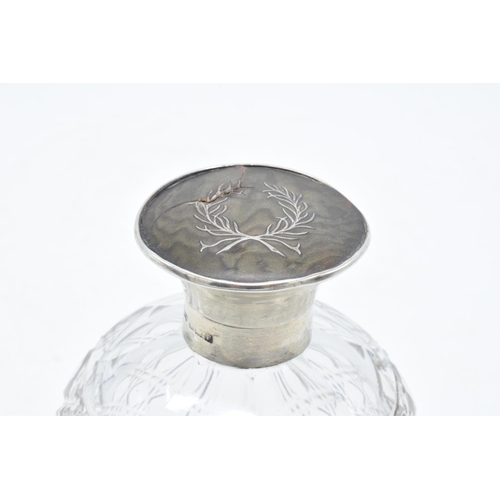 224 - A silver and glass scent bottle with a tortoiseshell style top. Hallmarks are rubbed. Crack to the t... 