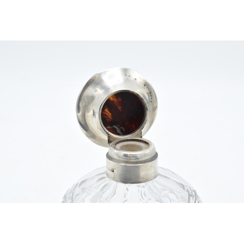 224 - A silver and glass scent bottle with a tortoiseshell style top. Hallmarks are rubbed. Crack to the t... 