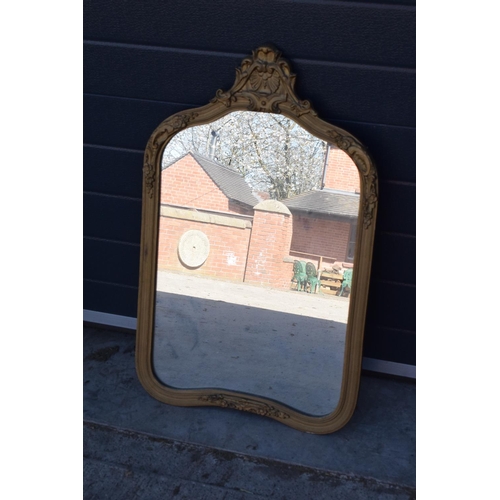 322 - An early 20th century gilt-effect ornate framed mirror. 83cm tall. A crack to the top ornate section... 