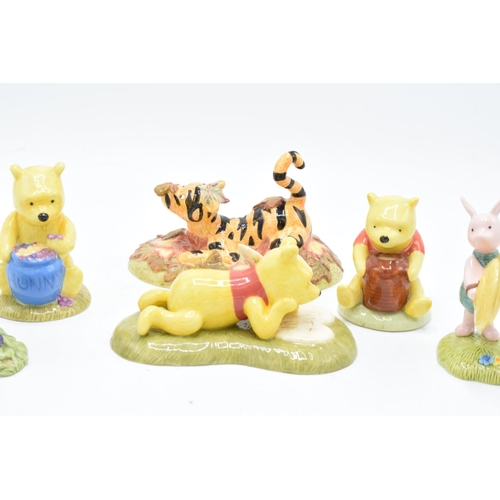 115 - A collection of Royal Doulton Winnie The Pooh figures to include All the flowers are waking up, Love... 