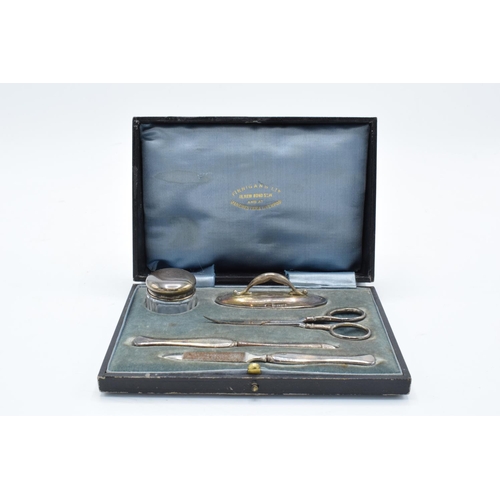 234 - A cased silver travelling manicure set to include scissors, nail file, lidded pot etc. Birmingham 19... 