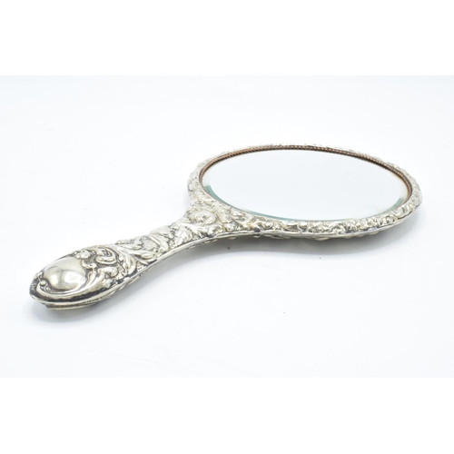 239 - An ornate embossed hand mirror, assumed silver plate.