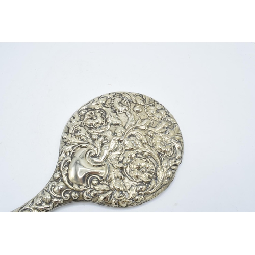 239 - An ornate embossed hand mirror, assumed silver plate.