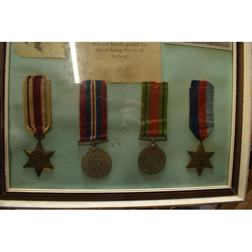 255 - A framed collection of militaria to include photos of soldiers, a message from the Under-Secretary o... 