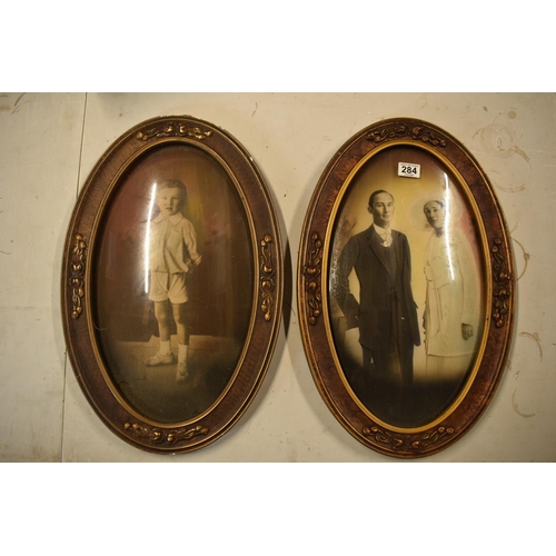 284 - A pair of Edwardian oval frames with scenes depicting a child and a couple. 58cm tall.