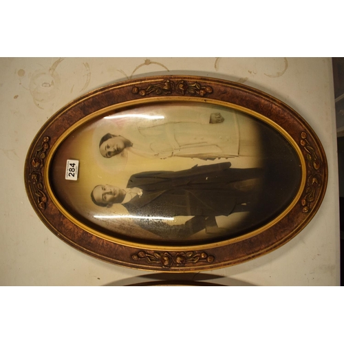 284 - A pair of Edwardian oval frames with scenes depicting a child and a couple. 58cm tall.