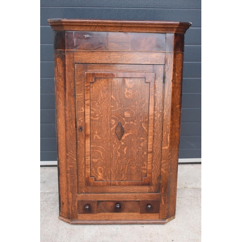 354 - A Georgian period oak corner cupboard with raised sections and a single drawer. 128cm tall, 82cm at ... 