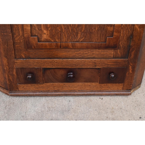 354 - A Georgian period oak corner cupboard with raised sections and a single drawer. 128cm tall, 82cm at ... 