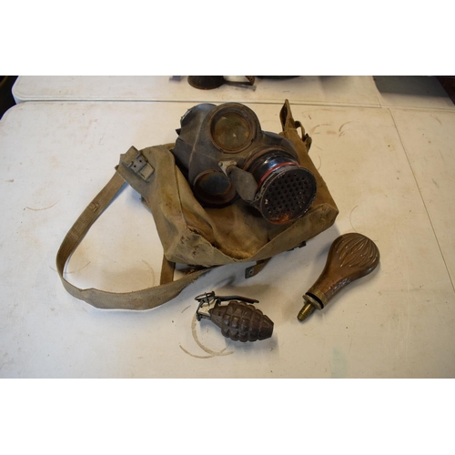 214 - A mixed collection of militaria items to include a 1939 gas mask in bag, a gun powder flash and a im... 