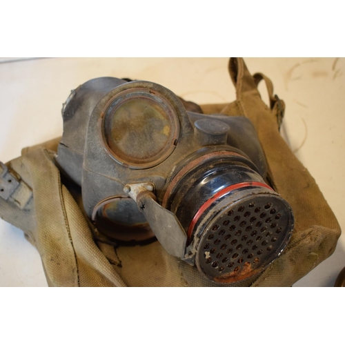 214 - A mixed collection of militaria items to include a 1939 gas mask in bag, a gun powder flash and a im... 