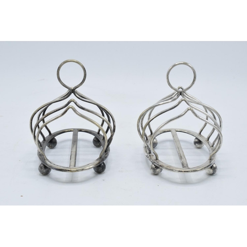 215A - A near pair of silver plated toast racks marked 'Harrods London'. 13cm diameter.