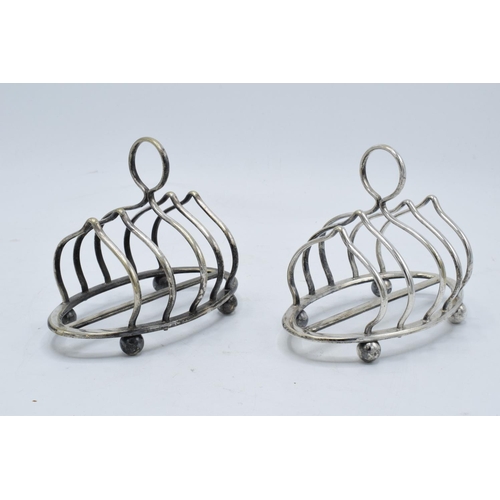 215A - A near pair of silver plated toast racks marked 'Harrods London'. 13cm diameter.