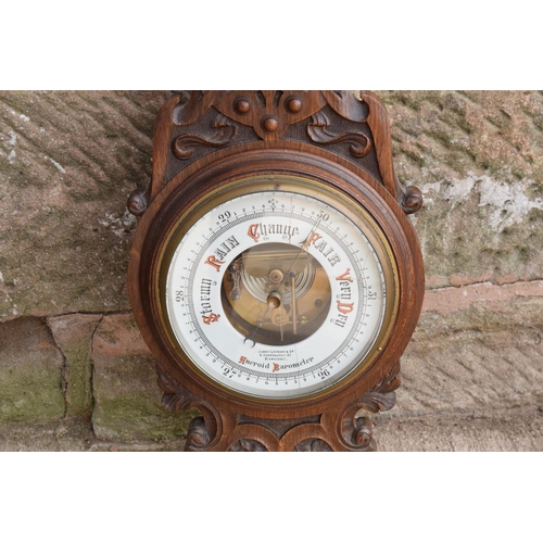 247 - A late Victorian/ Edwardian arts and crafts style carved aneroid barometer by James Lucking and Co, ... 