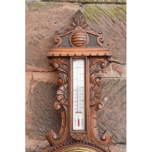 248 - A late Victorian/ Edwardian arts and crafts style carved aneroid barometer. 109cm tall. There are so... 