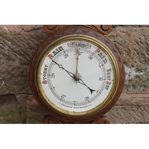 249 - A late Victorian/ Edwardian arts and crafts style carved aneroid barometer. 105cm tall. There are so... 